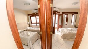 A hotel room with two beds, a wooden door, and a window with curtains. - Pousada Cristalmar (Bombinhas)
