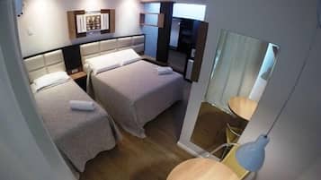 Una habitación de hotel con dos camas, un escritorio pequeño, una silla, un espejo y una lámpara.