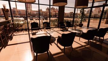 A spacious indoor area with large windows, multiple chairs, and tables arranged for seating.