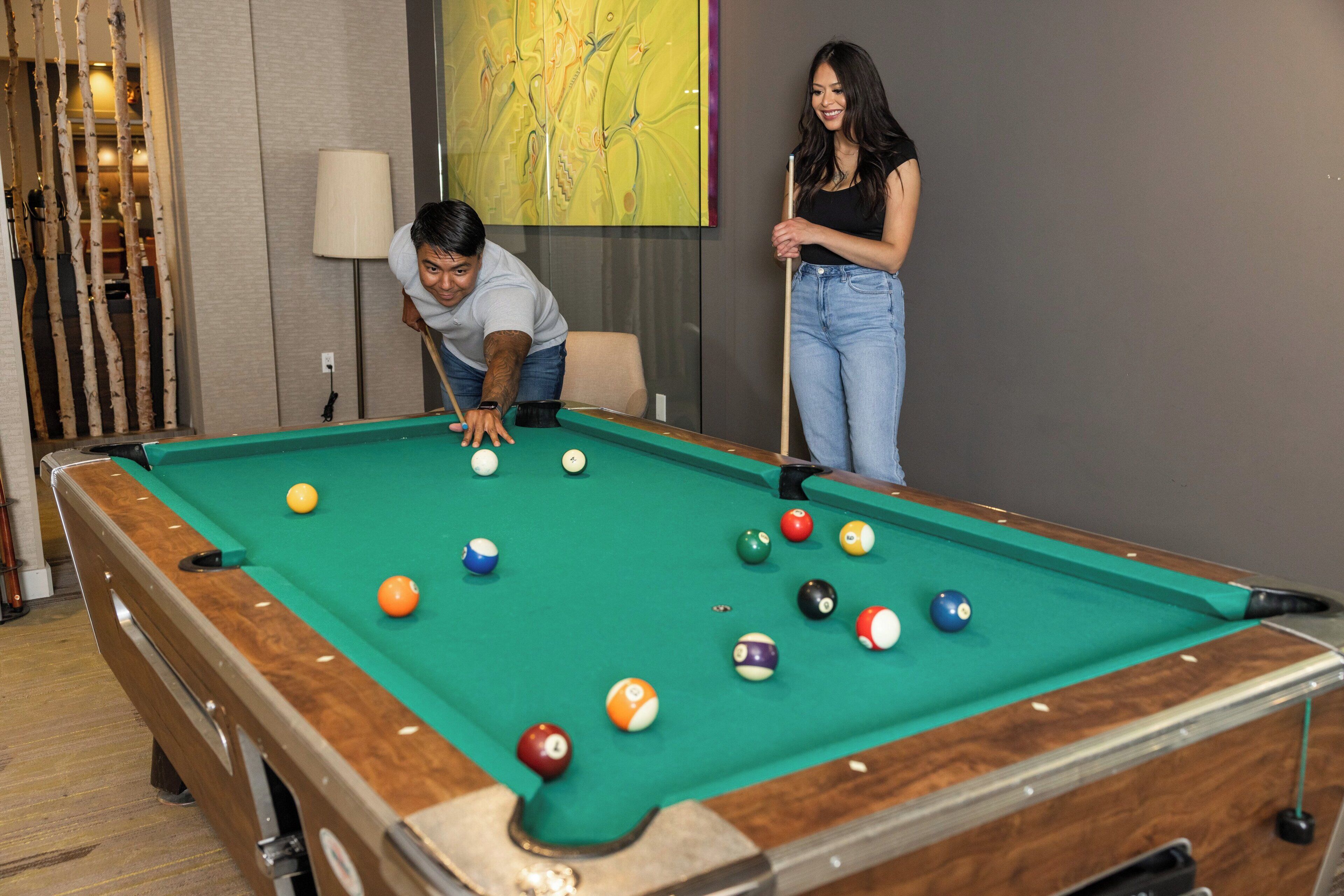 Une table de billard avec des billes, une lampe et un tableau accroché au mur.