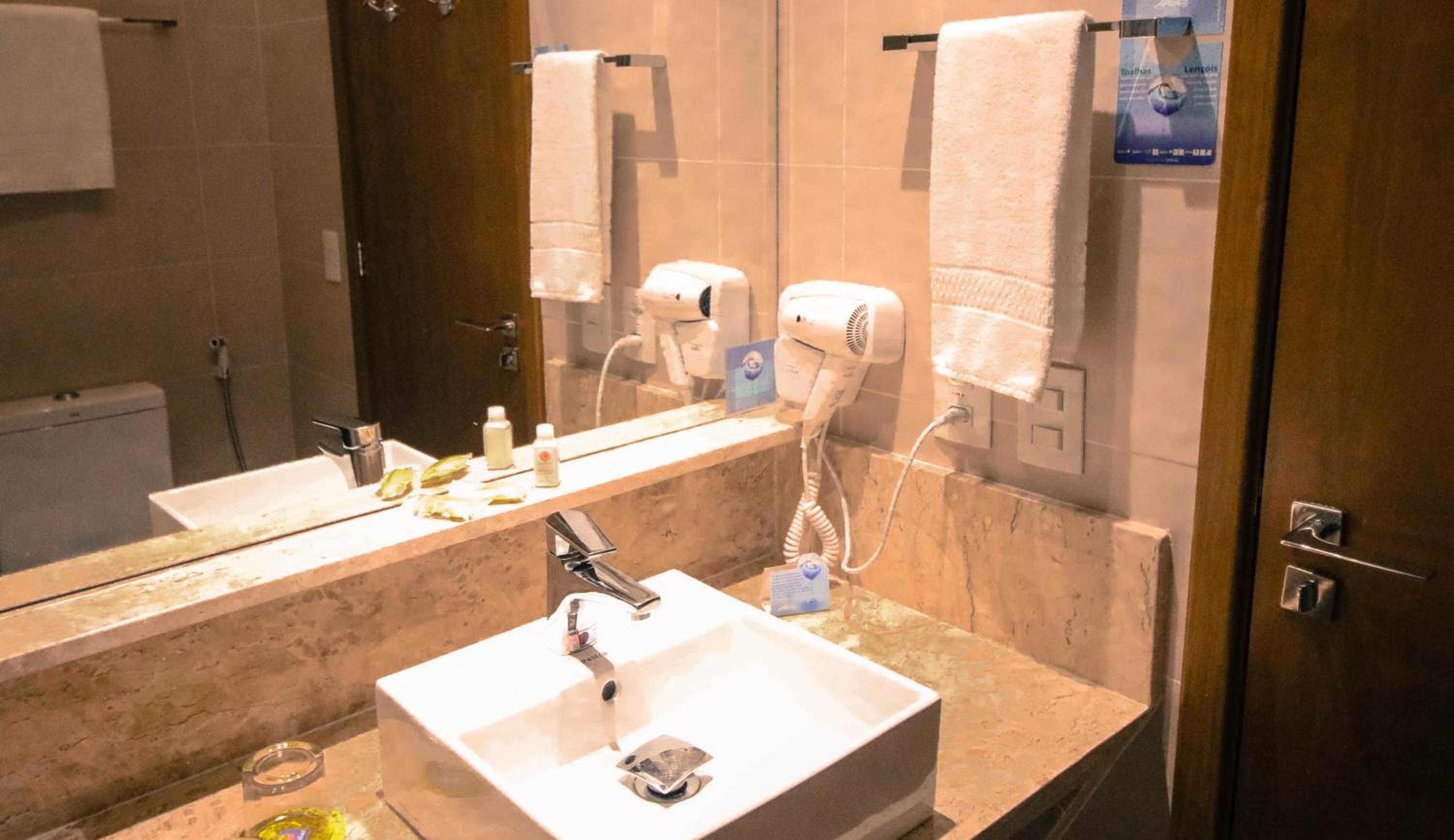 A modern bathroom with a large mirror, a sink, and two hair dryers mounted on the wall.
