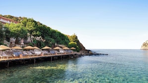 A pier with sun loungers and umbrellas overlooking clear blue water. - Wyndham Datca Perili Bay (Datça)