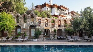 A stone building with a pool and lounge chairs. - Wyndham Datca Perili Bay (Datça)