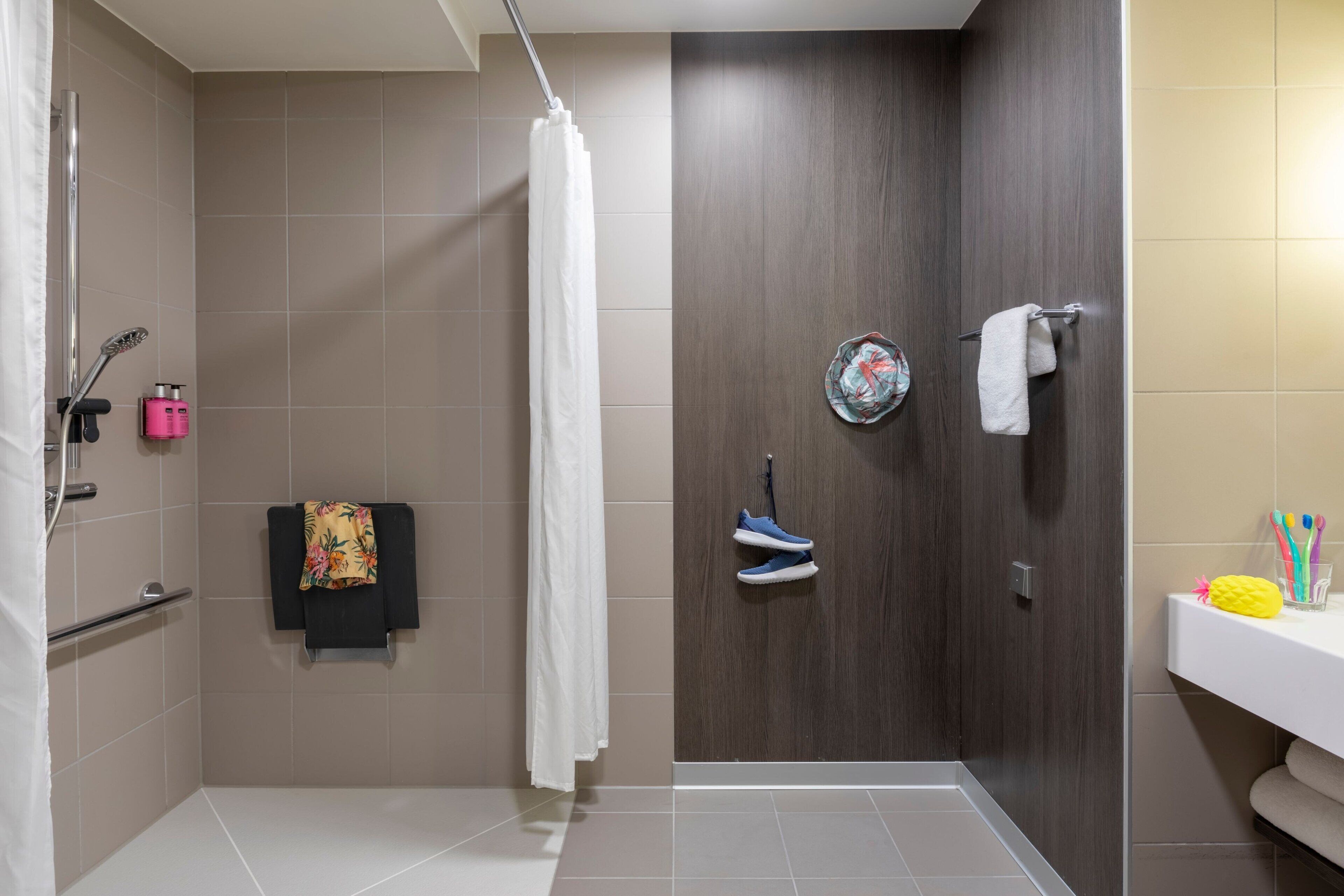 A modern bathroom with a shower, a towel rack, and a sink area.