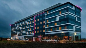 A multi-story hotel with a modern design, featuring a prominent neon sign and a well-lit entrance. - Moxy Aberdeen Airport (Aberdeen)