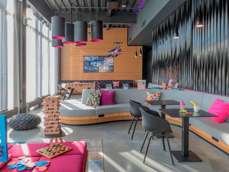 A modern lounge area with a curved sofa, black chairs, a small table, and a large window.