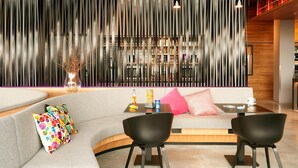 A modern interior with a curved sofa, black chairs, a small table, and a decorative wall with vertical slats. - Moxy Aberdeen Airport (Aberdeen)