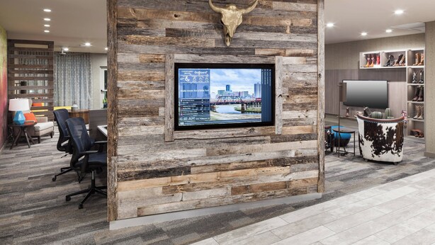A modern office space with a rustic wooden wall, a mounted TV, and a shoe display.