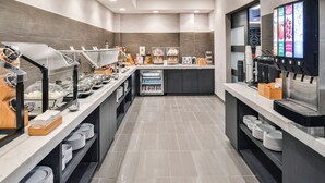 A modern breakfast area with self-service stations, including coffee machines and a refrigerated display case. - Fairfield Inn & Suites by Marriott Raleigh Cary (Cary)