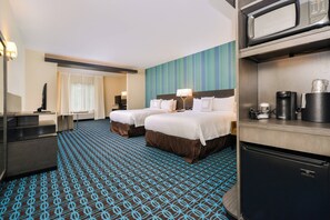A hotel room with two beds, a kitchenette, a flat-screen TV, and a large window with curtains.