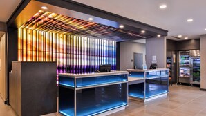A modern reception area with a glass display case, a digital screen, and a refrigerator stocked with beverages. - Fairfield Inn & Suites by Marriott Raleigh Cary (Cary)