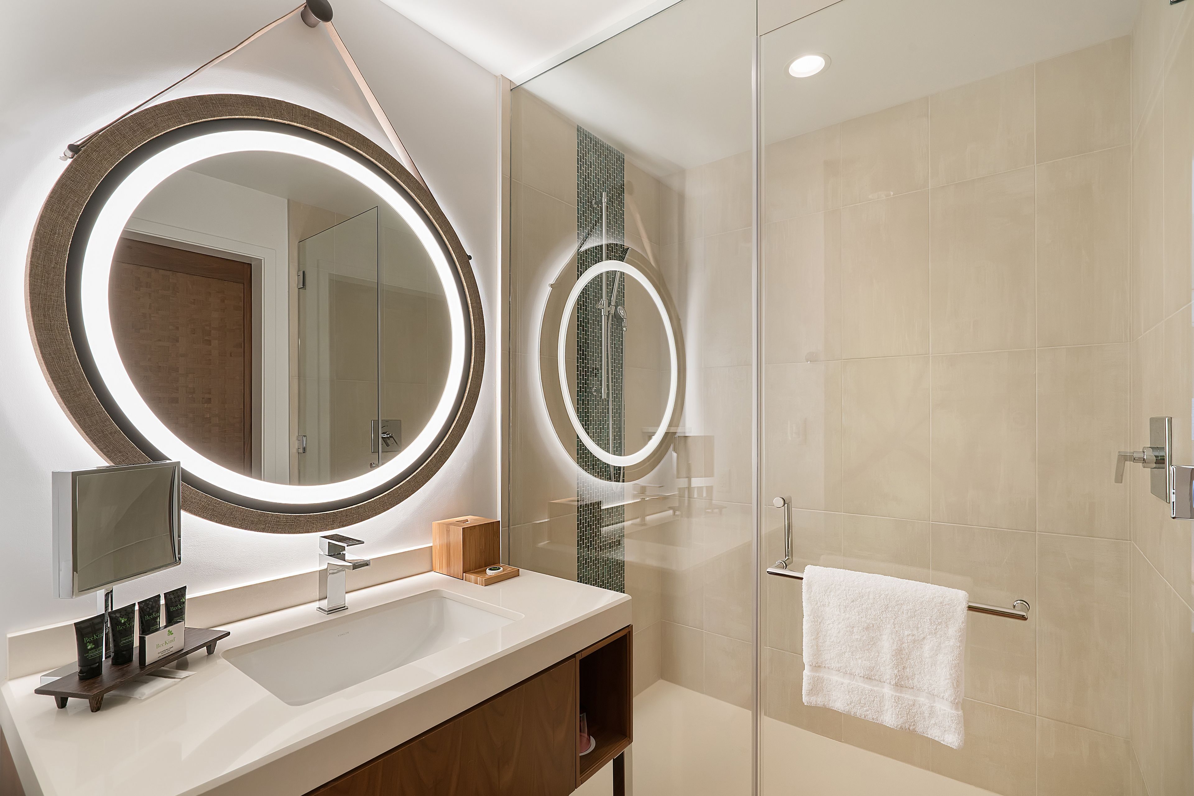 A modern bathroom with a large mirror, a sink, and a glass shower enclosure.