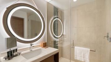 A modern bathroom with a large mirror, a sink, and a glass shower enclosure.