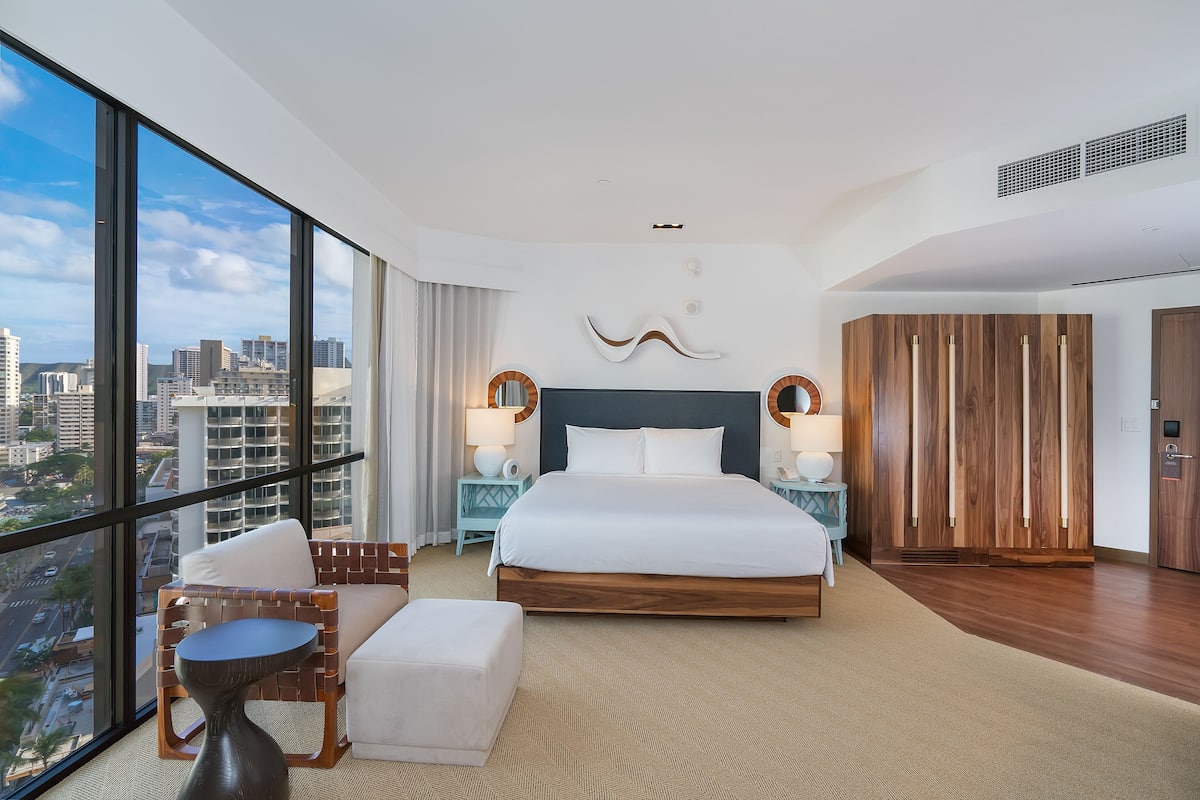 A modern hotel room with a large bed, a view of the city, and a balcony.