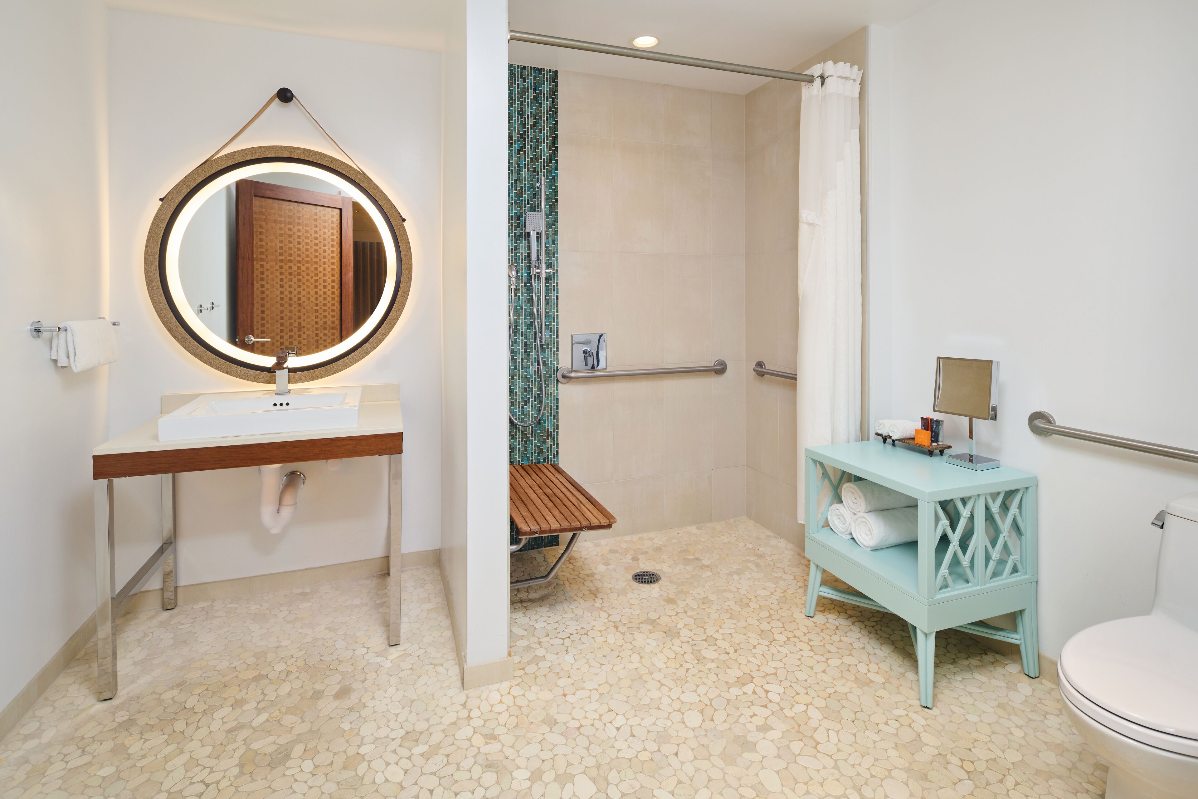 Un baño con un espejo redondo, un lavabo, una ducha y un inodoro.