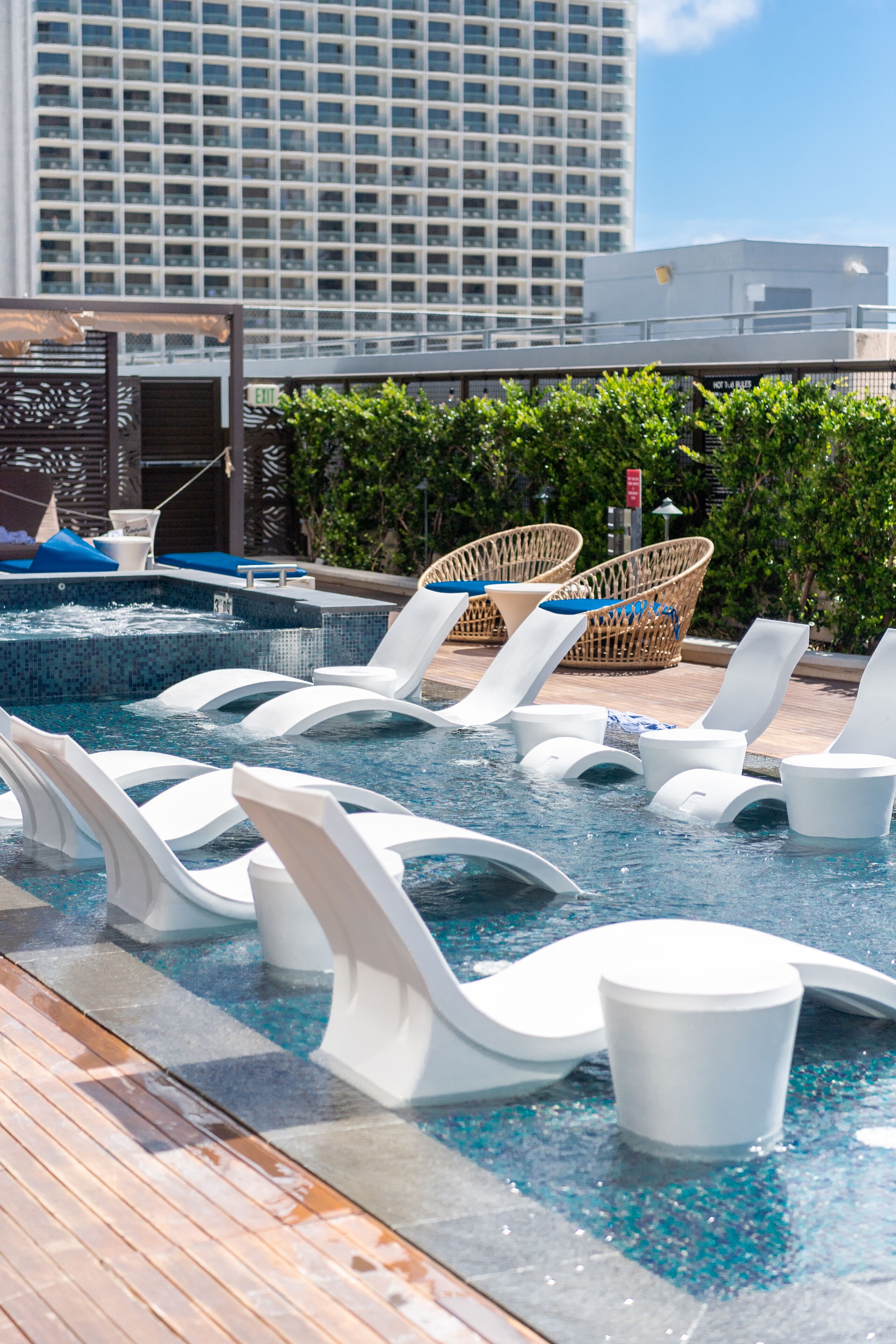 A rooftop pool area with lounge chairs and a hot tub.