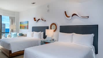 Habitación de hotel con dos camas, un ventanal grande y vistas al horizonte de la ciudad.