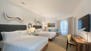 A hotel room with two beds, a desk, a TV, and a painting on the wall.