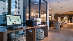 A modern reception desk with computers, a large window, and a seating area with wicker chairs.