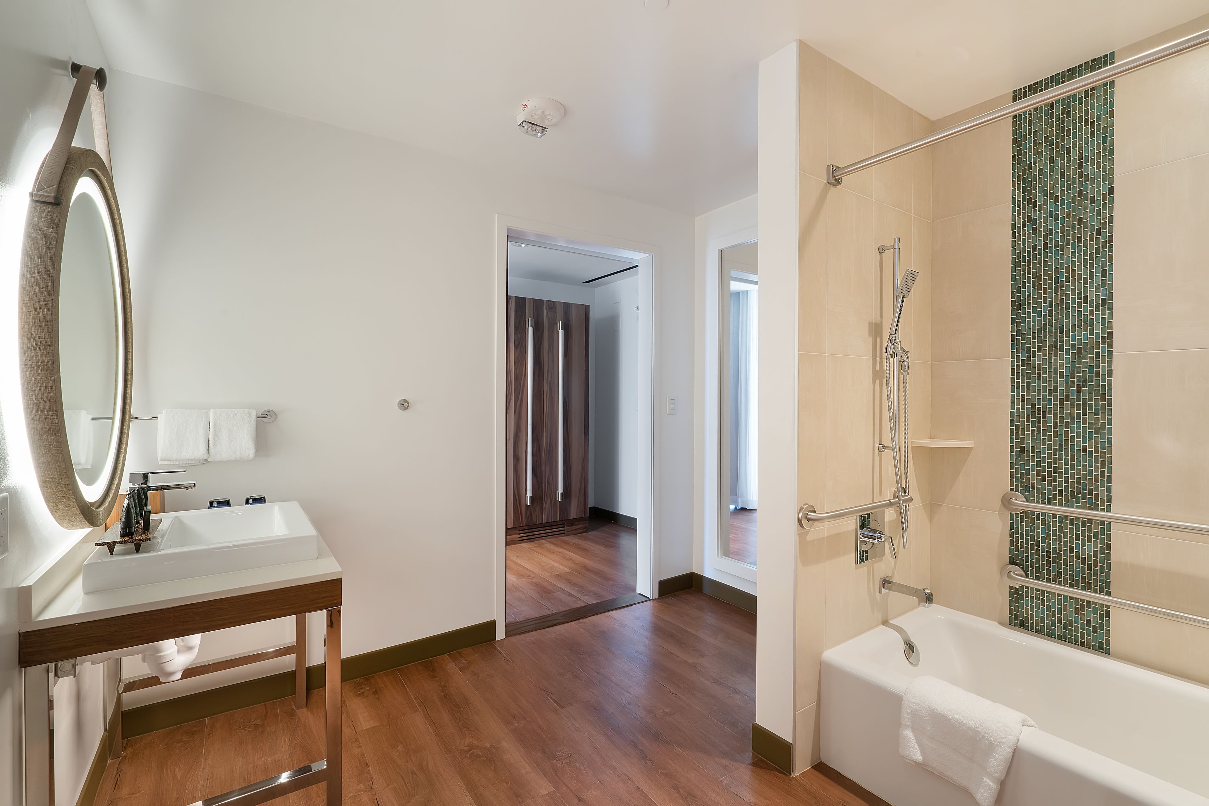 A bathroom with a sink, mirror, and shower.
