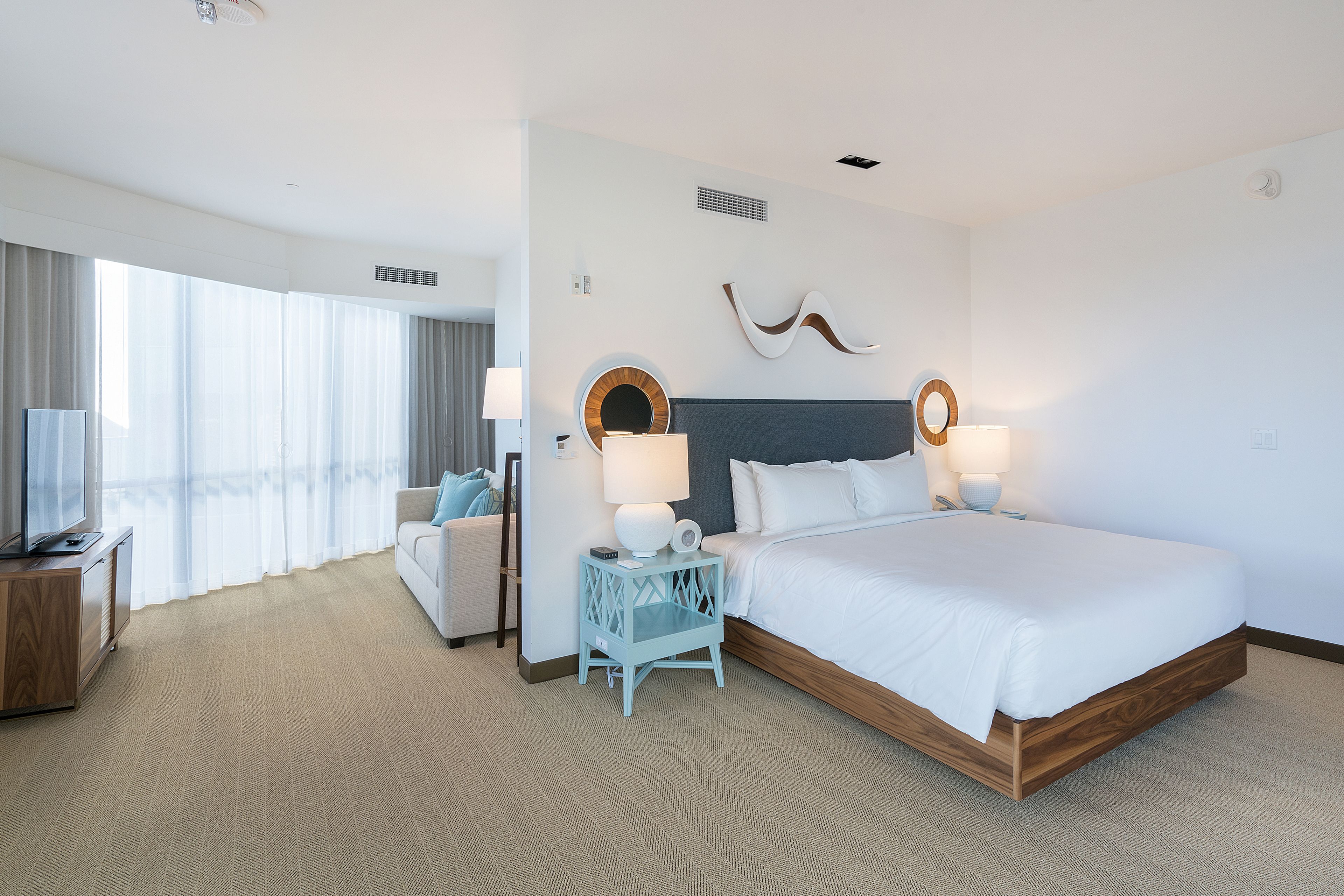 Habitación de hotel con una cama grande, televisión, escritorio y vistas al exterior.