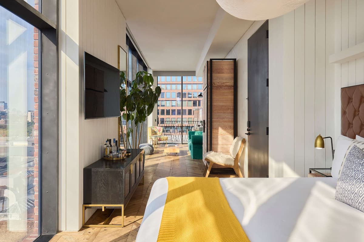 Une chambre d’hôtel moderne dotée d’un grand lit, d’un bureau, d’une télévision et offrant une vue sur la ville.