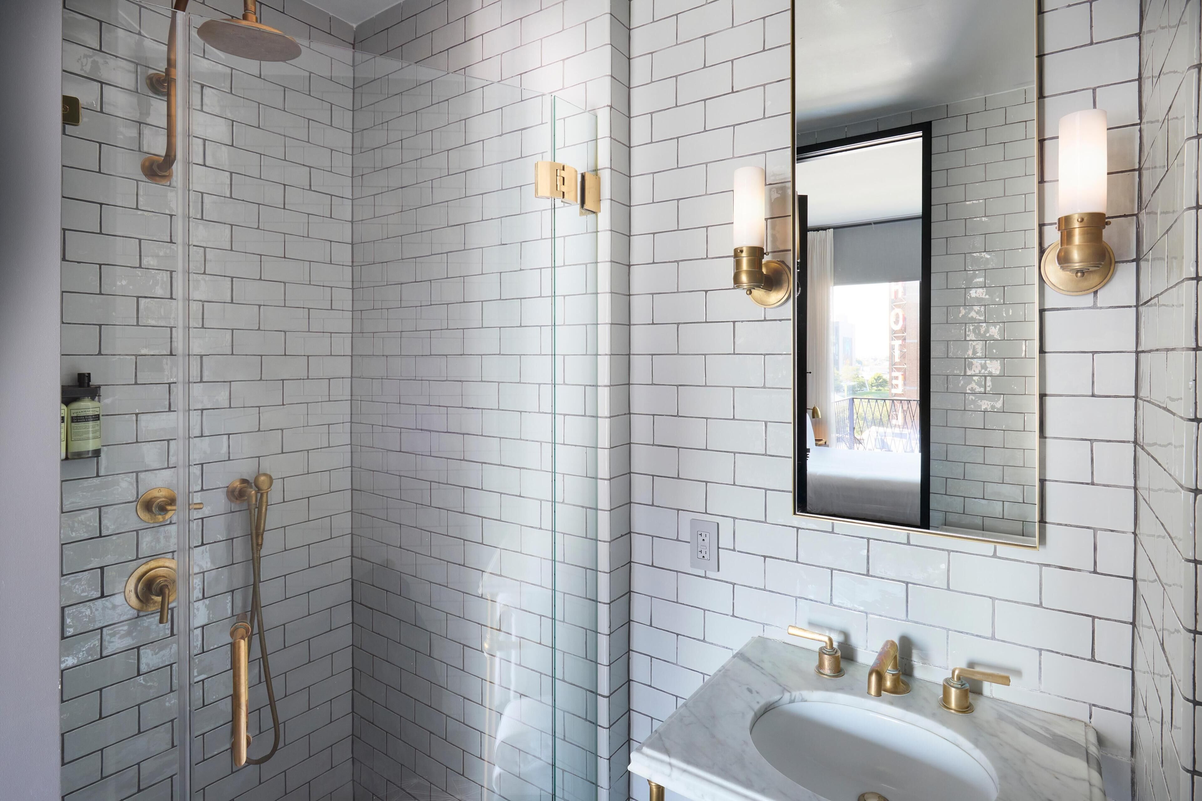 A bathroom with white subway tiles, a marble sink, and gold fixtures.