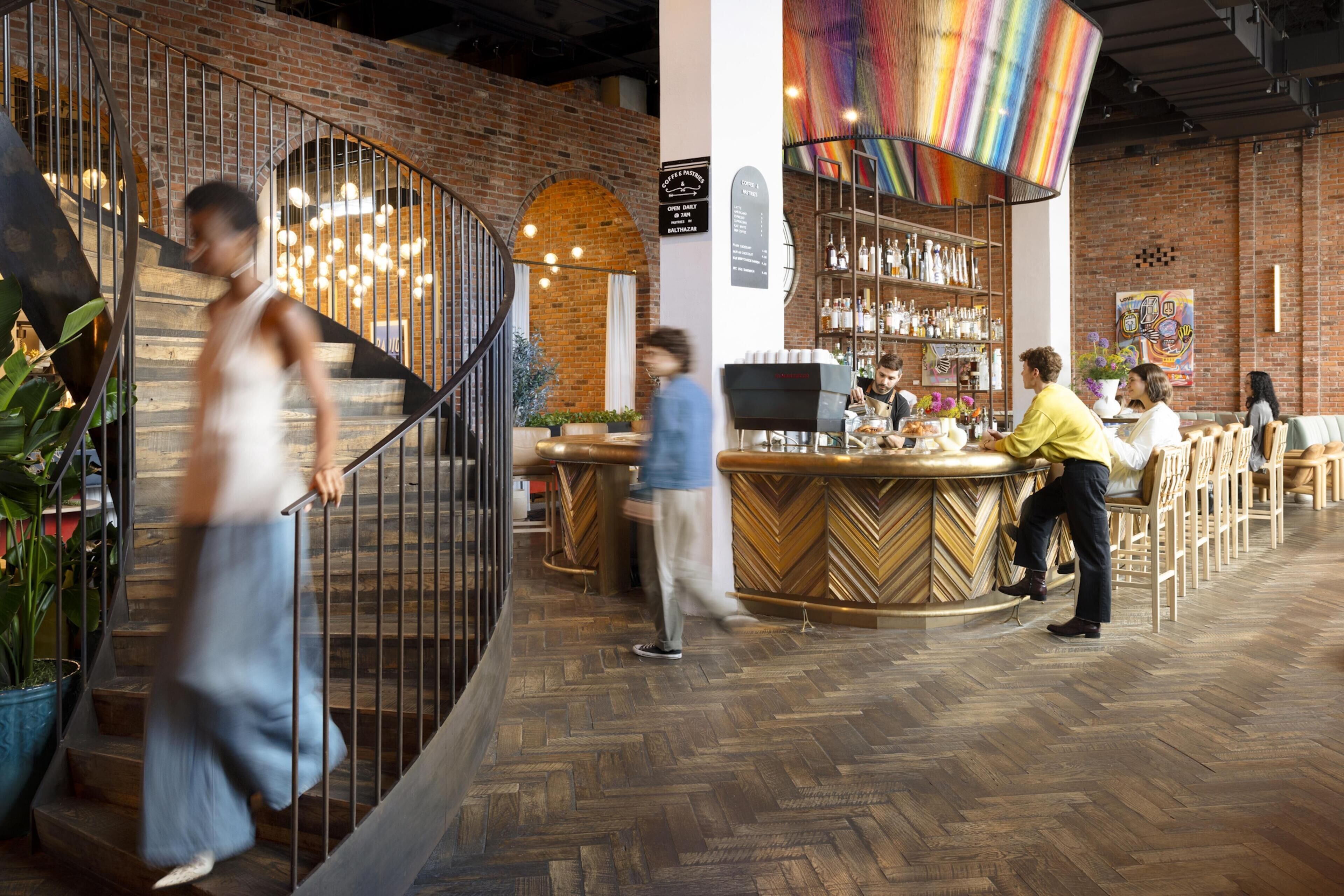 A bar area with a herringbone floor, a bar counter, and a variety of bottles on shelves.