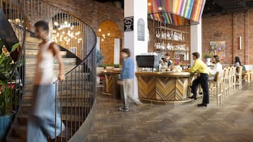 A bar area with a herringbone floor, a bar counter, and a variety of bottles on shelves.
