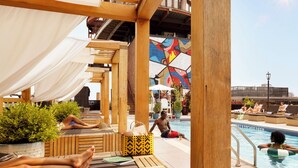 A poolside area with wooden loungers, a pool, and a mural.