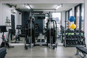 A gym with exercise equipment, a mirror, and a rack of dumbbells.