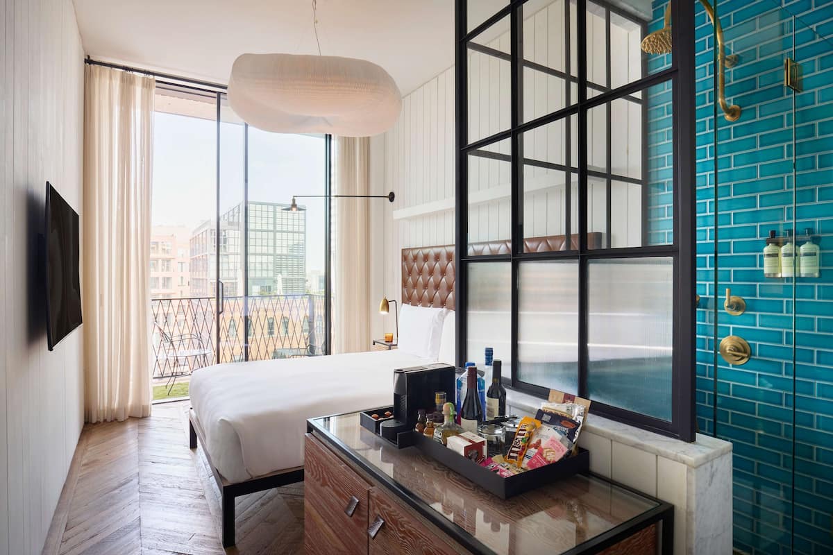 Une chambre d’hôtel dotée d’un grand lit, d’une table basse en verre, d’un minibar et offrant une vue sur la ville grâce à de grandes fenêtres.