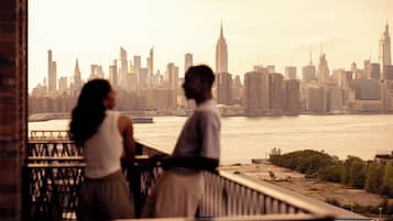 Une vue sur les gratte-ciel d’une ville, avec notamment l’Empire State Building, prise depuis un balcon doté d’une balustrade.