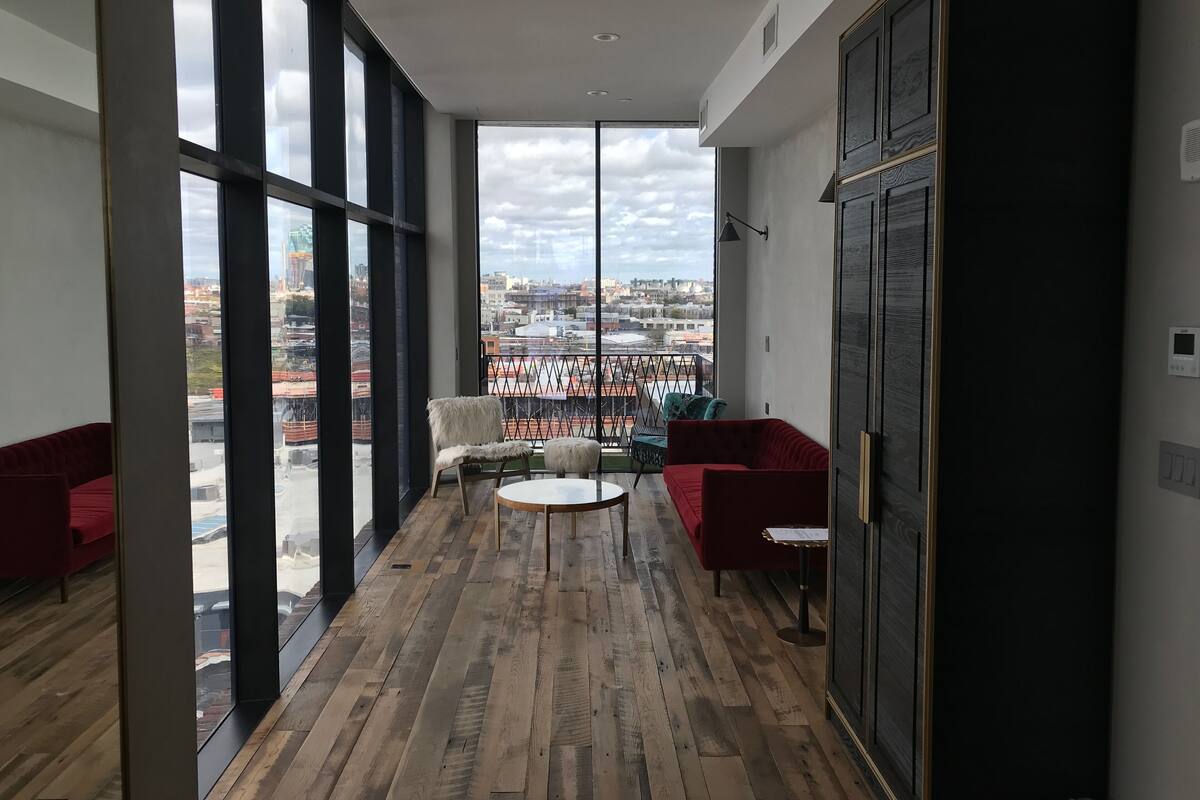 Un interior moderno con ventanas amplias, suelo de madera y muebles rojos.