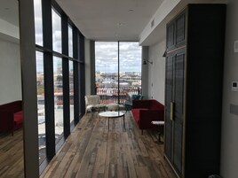 A modern interior with large windows, a wooden floor, and red furniture.