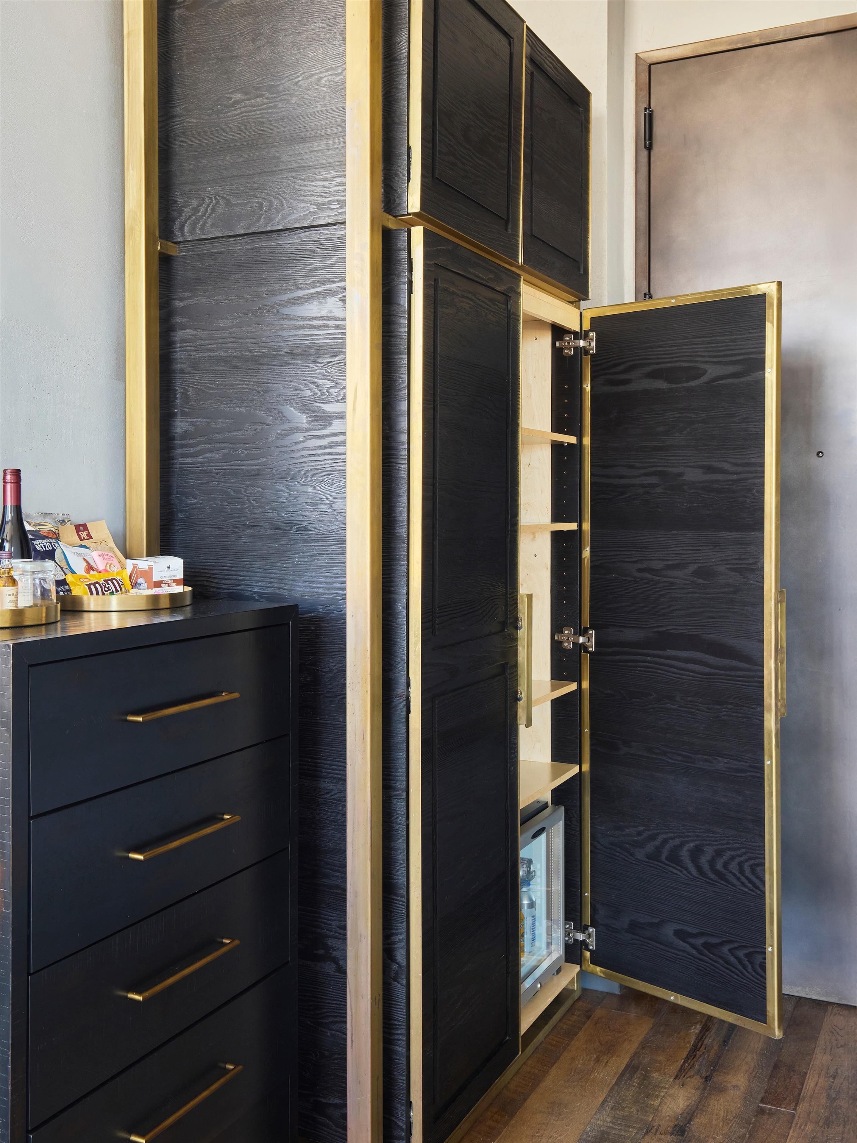 A room with a black wardrobe with gold accents, a small table with snacks, and a door.