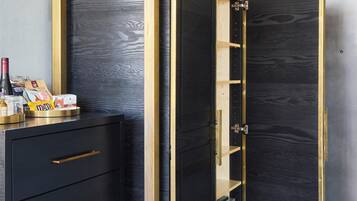 A room with a black wardrobe with gold accents, a small table with snacks, and a door.