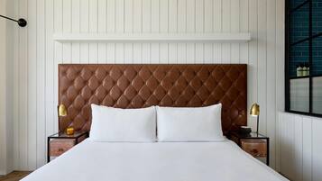 A bed with a tufted headboard, two bedside tables with lamps, and a window with a view of the outside.