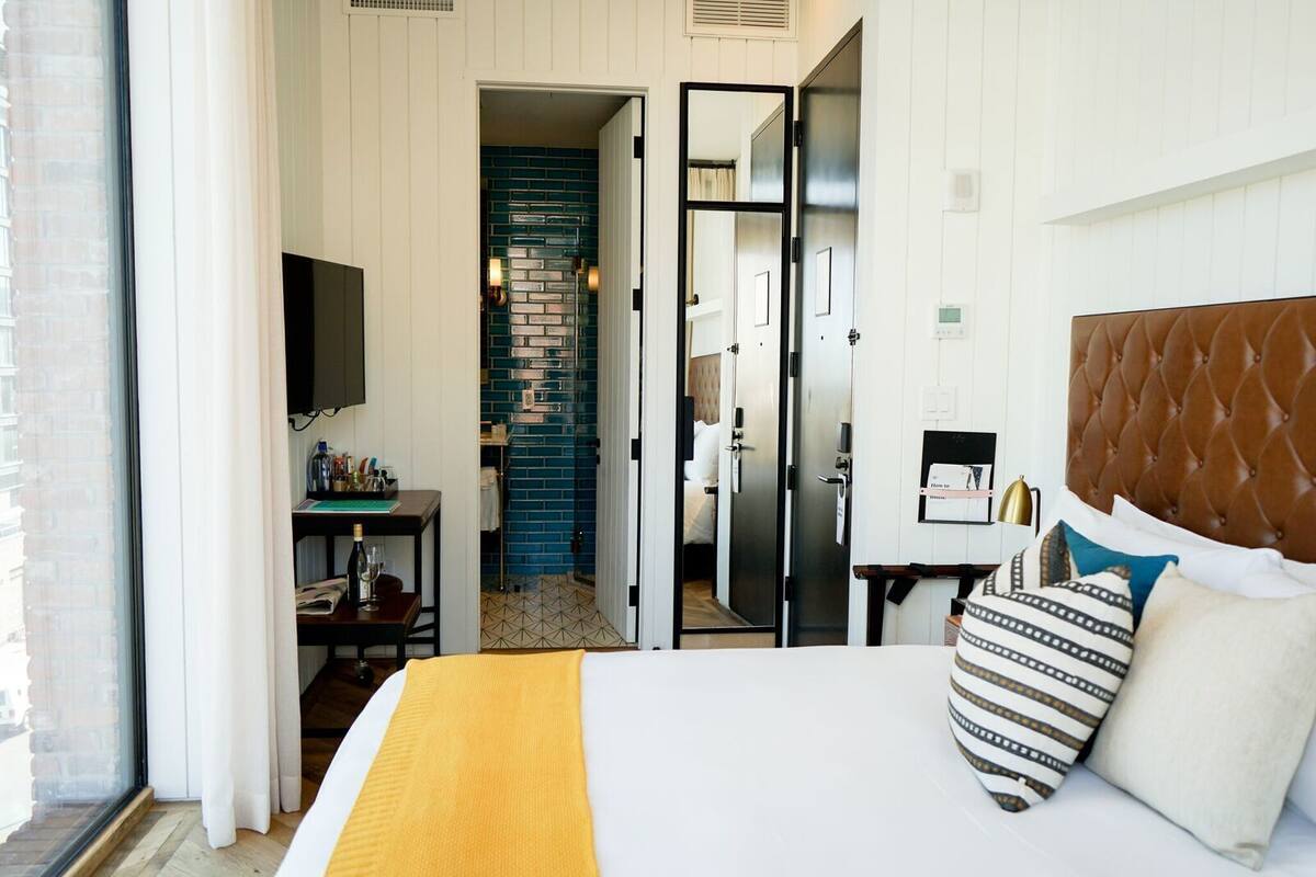 Une chambre d’hôtel avec un lit, une télévision, un bureau et une salle de bain, le tout visible à travers une porte ouverte.