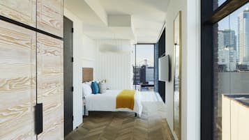 Quarto de hotel moderno com uma cama grande, vista para a cidade e piso de madeira.