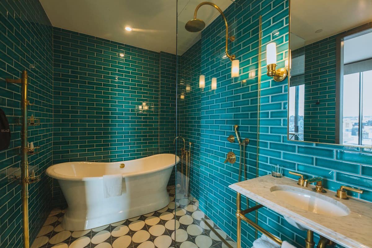 Un baño con una bañera independiente, un tocador con lavabo y un espejo grande.
