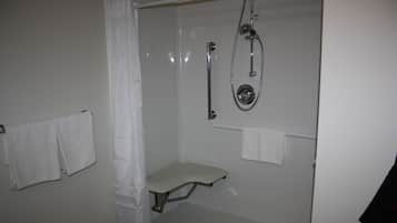 A small, enclosed shower area with a bench, a handheld showerhead, and a wall-mounted towel rack.