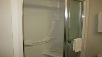 A bathroom with a glass shower enclosure, a toilet, and a towel rack.