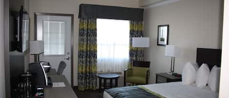Una habitación de hotel con cama, escritorio, silla y una pequeña mesa.