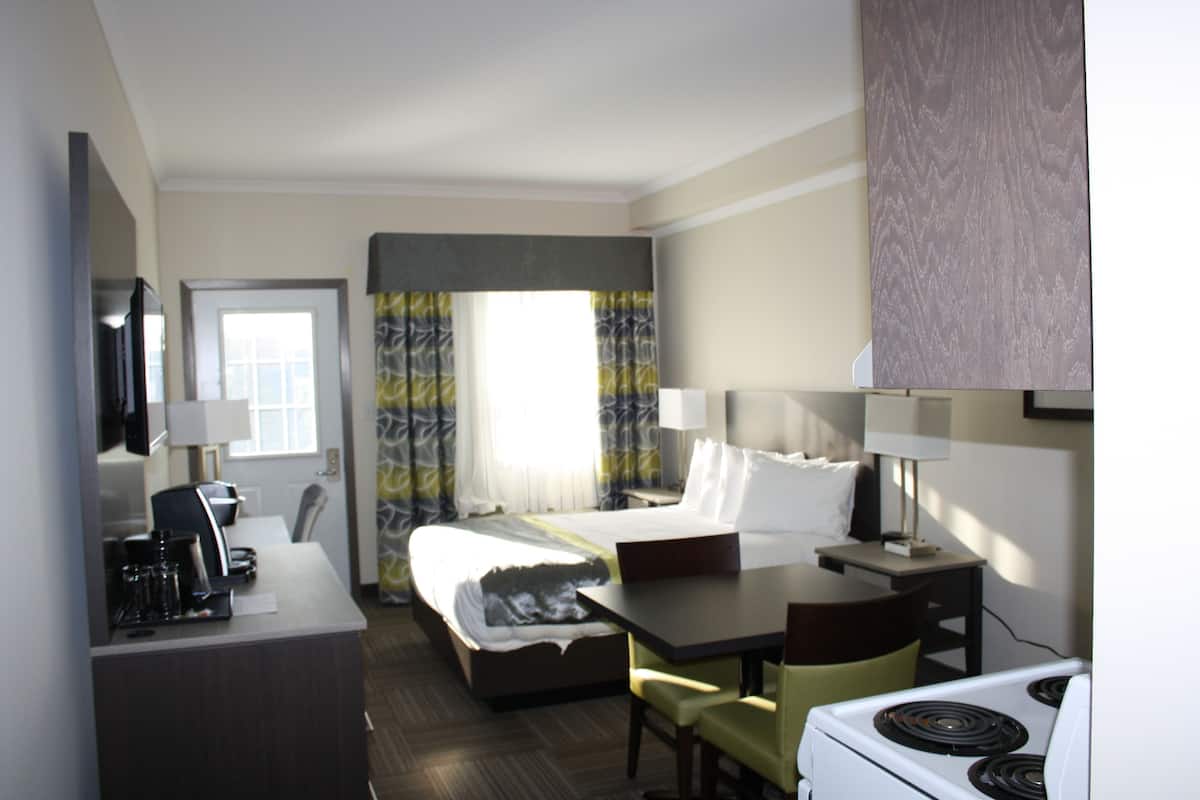Una habitación de hotel con cama, escritorio, silla, televisión y cocina.