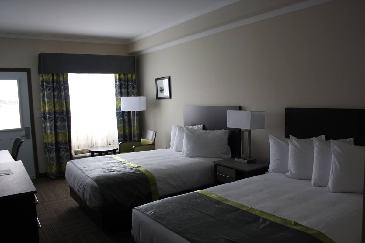Habitación de hotel con dos camas, un escritorio y una silla.