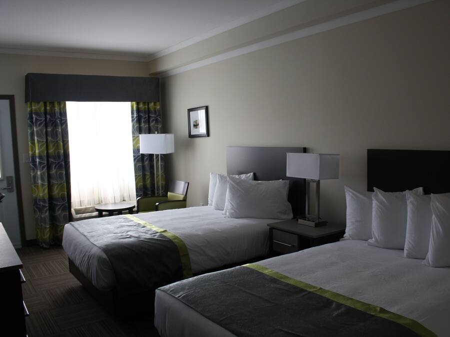 A hotel room with two beds, a desk, and a chair.