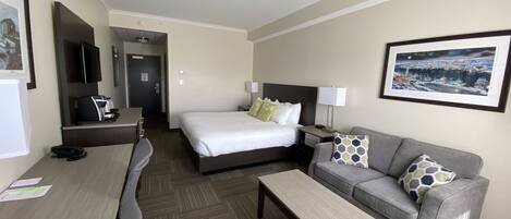 Una habitación de hotel con cama, sofá, escritorio y televisión.