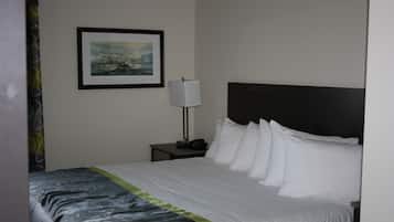 Una habitación de hotel con una cama bien hecha, un cuadro en la pared, una lámpara de noche y una mesita de noche.