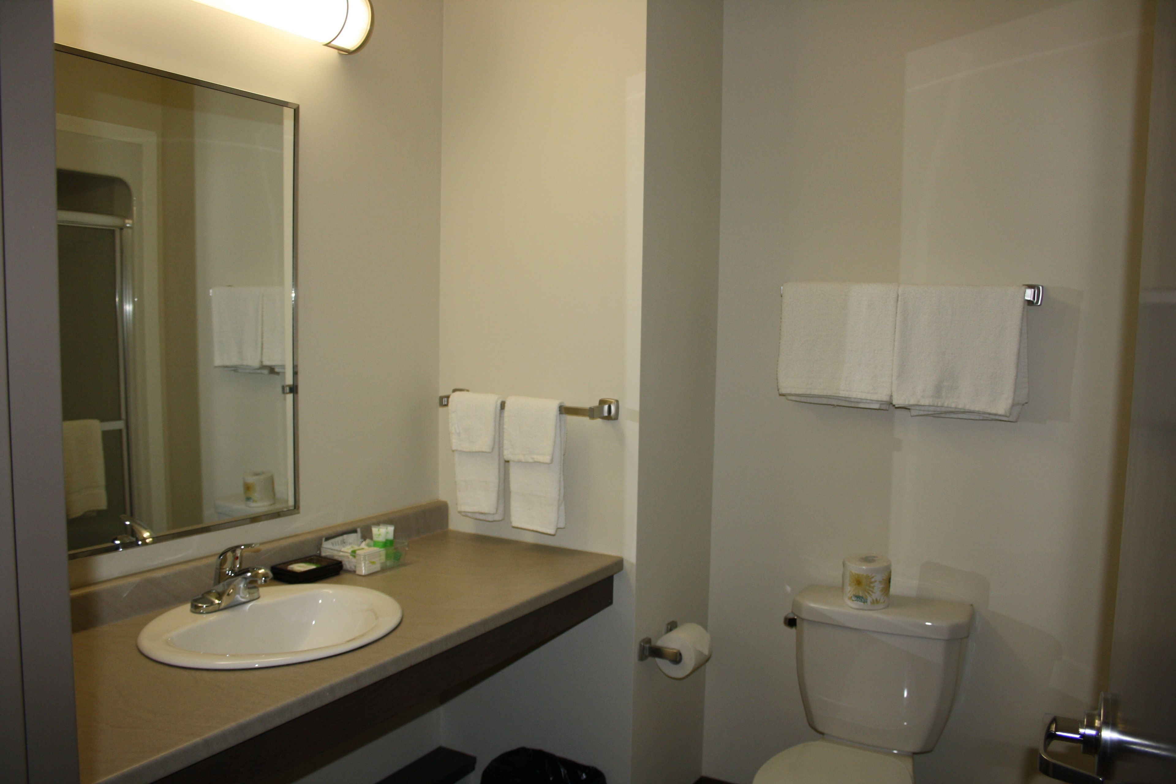 A bathroom with a sink, mirror, toilet, and towel rack.